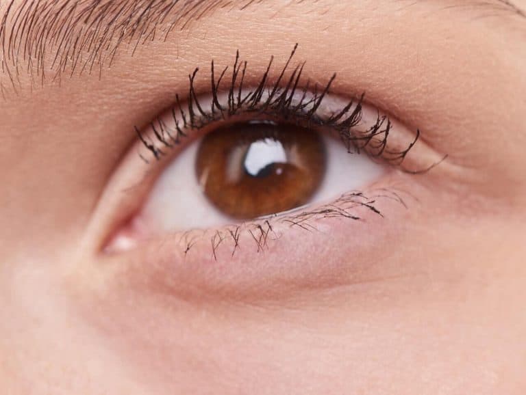 Close-up of a brown eye with long eyelashes, showcasing eye makeup details.