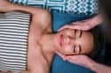 Person receiving a facial massage, relaxing with eyes closed on a spa table.